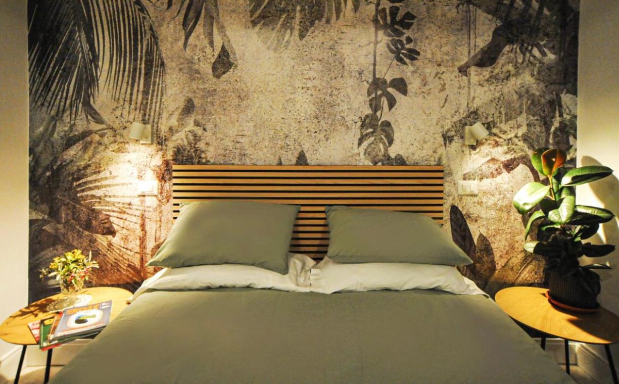 Camera doppia con letto matrimoniale e parete decorata a foglie