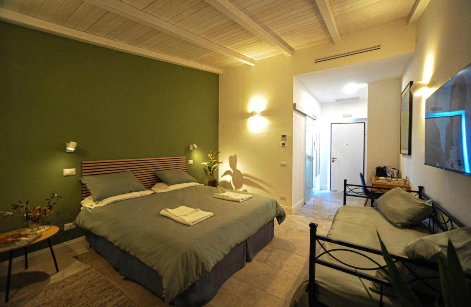 Camera tripla con parete verde, letto matrimoniale e letto singolo