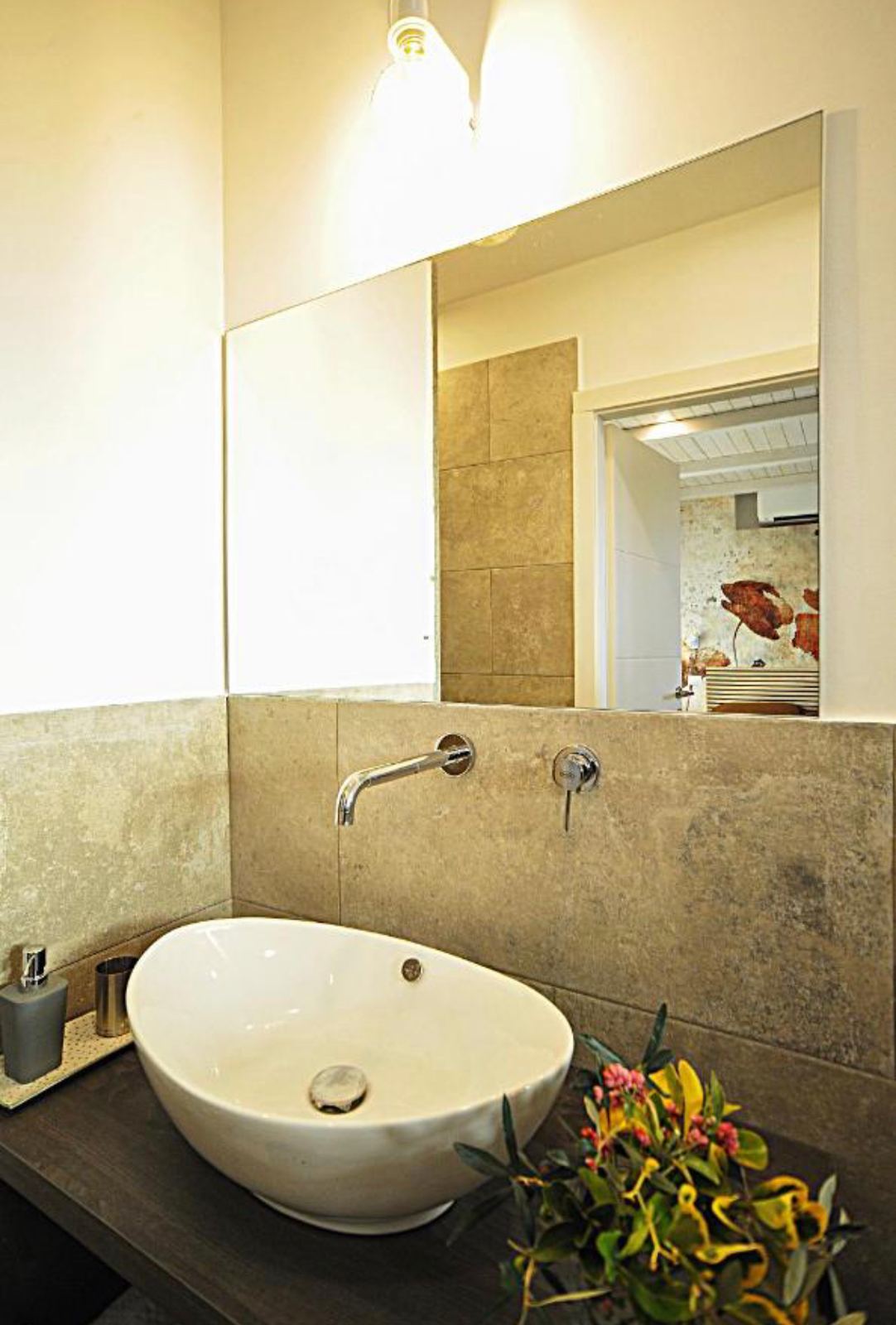 Il bagno, con lavabo in appoggio e rivestimento in pietra