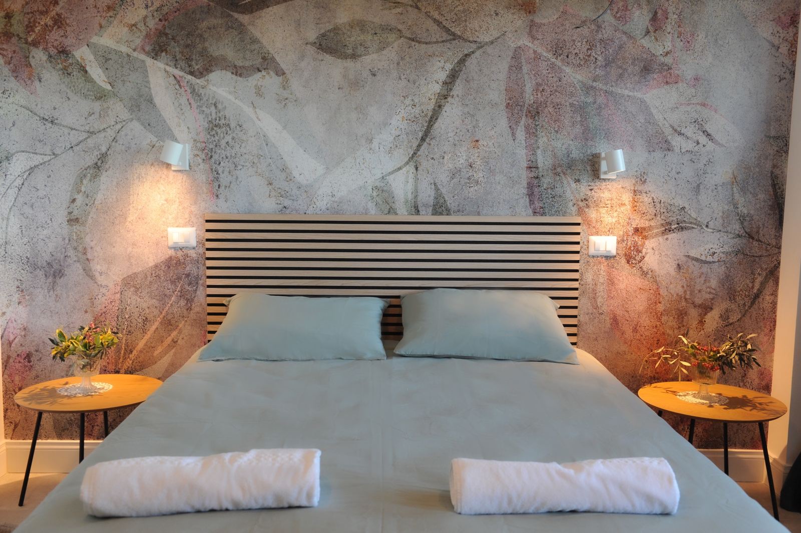 Camera doppia con letto matrimoniale e parete decorata a grandi foglie