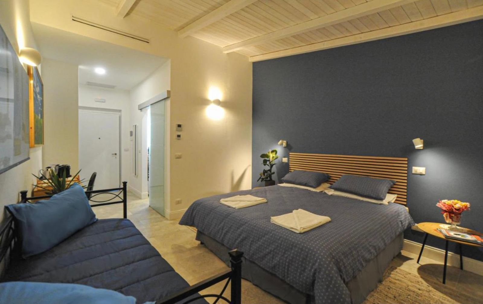 Camera tripla con parete blu, letto matrimoniale e letto singolo