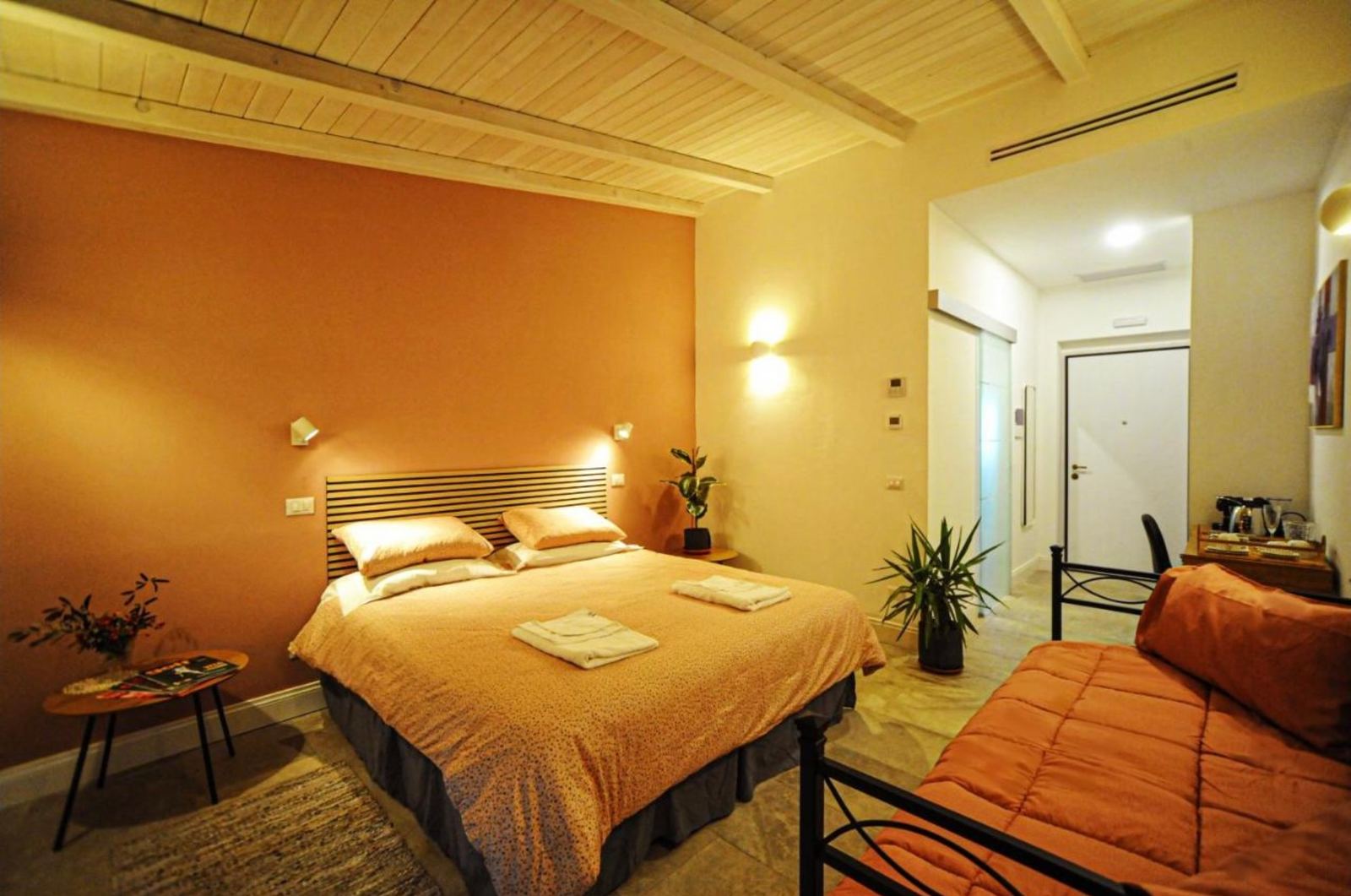 Camera tripla con parete arancione, letto matrimoniale e letto singolo